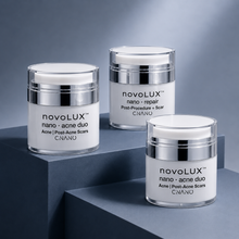 Three white and silver jars of CNANO nanoLUX skincare products arranged on dark gray geometric blocks against a blue-gray background.