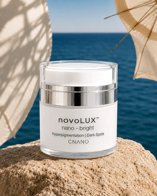 novoLUX nano bright skincare cream jar on a sunlit coastal rock with ocean and beach umbrella background for hyperpigmentation and dark spots.